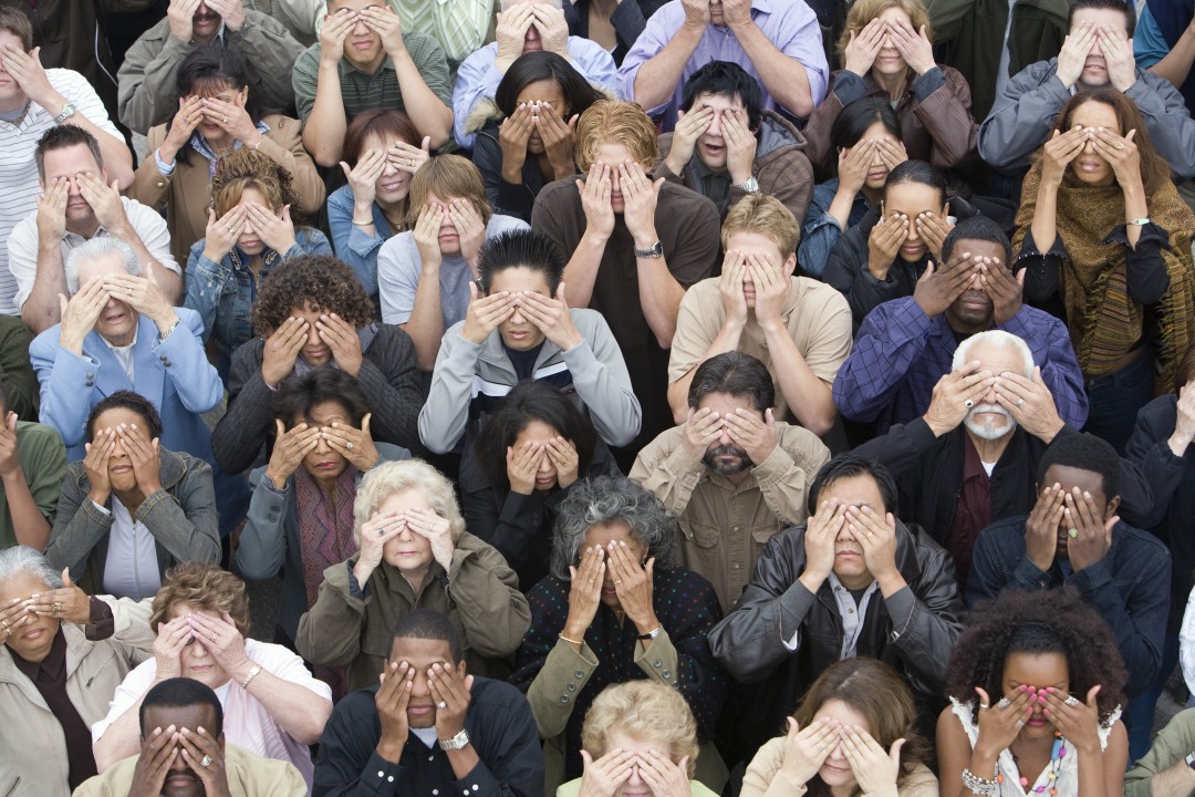 A crowd of people covering their eyes.