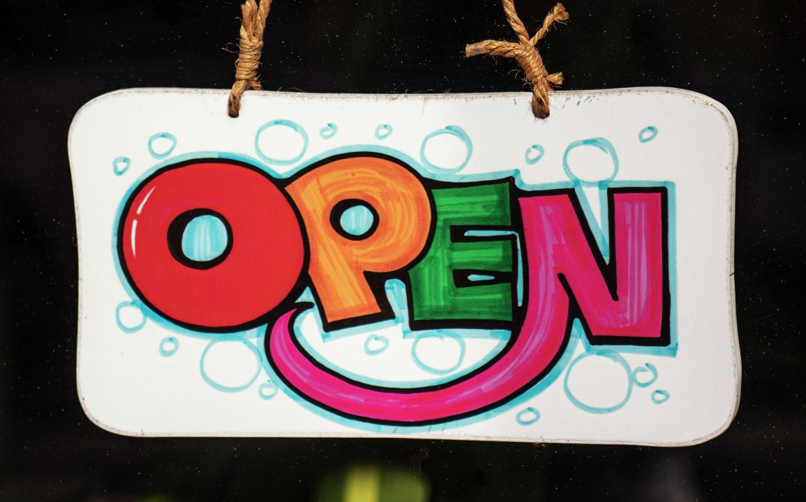 A hand made, brightly coloured sign with the word OPEN.