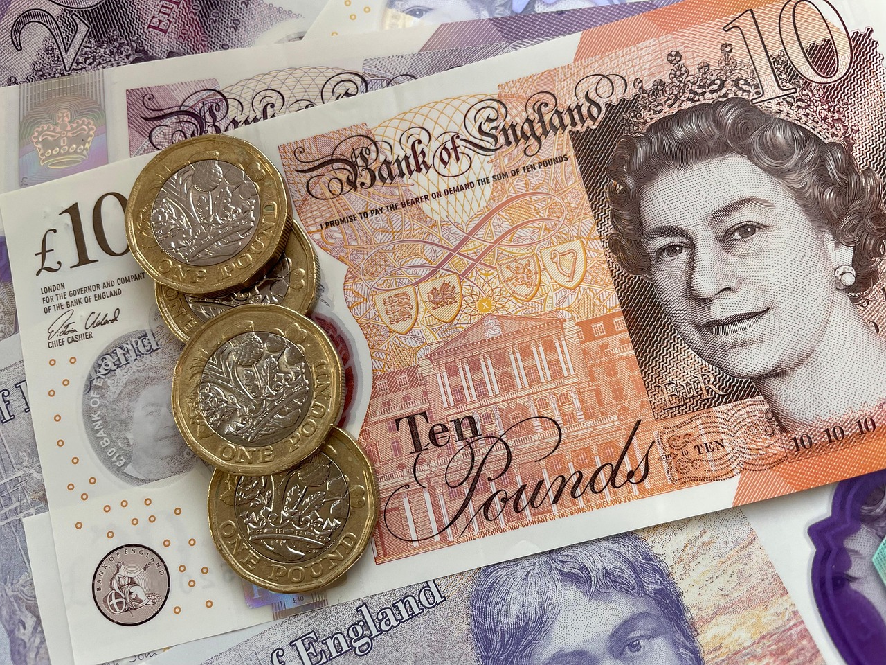 British pound notes with pound coins on top.