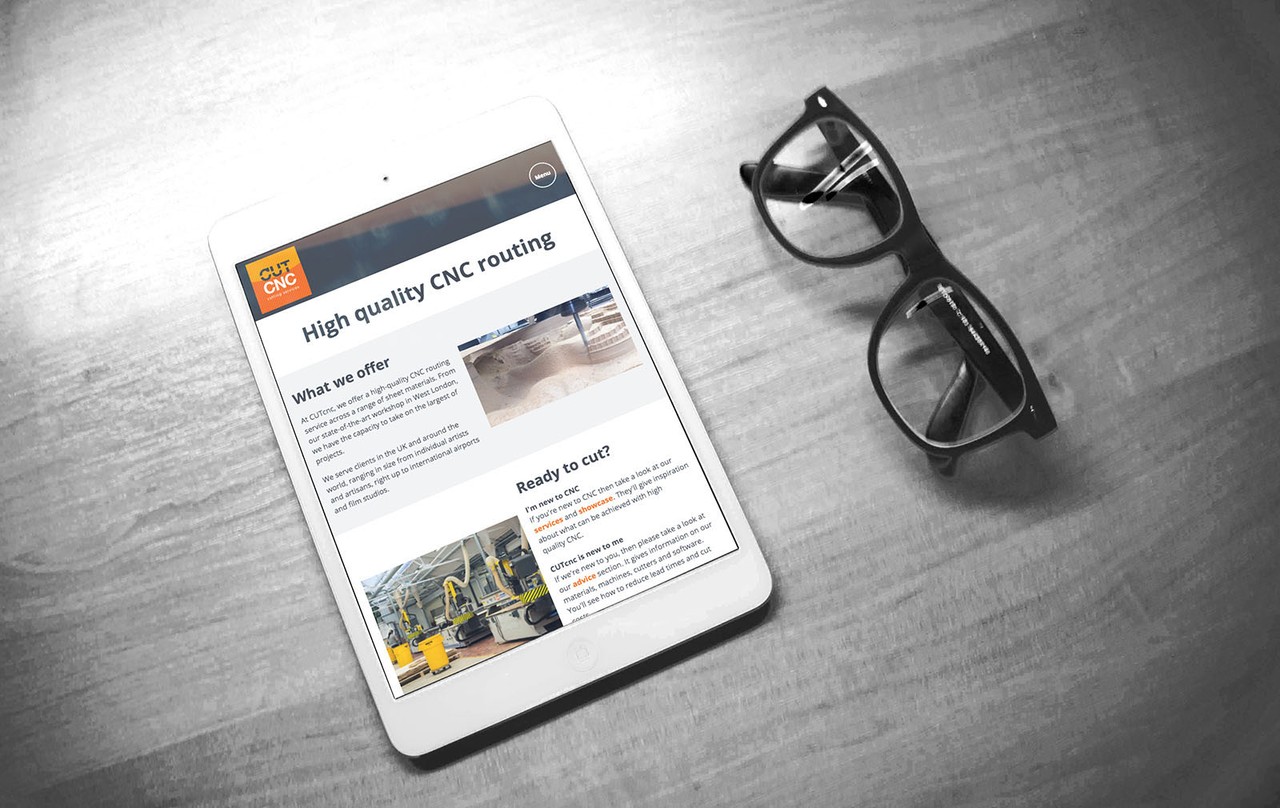 The CUTcnc homepage on an iPad, next to a pair of glasses.