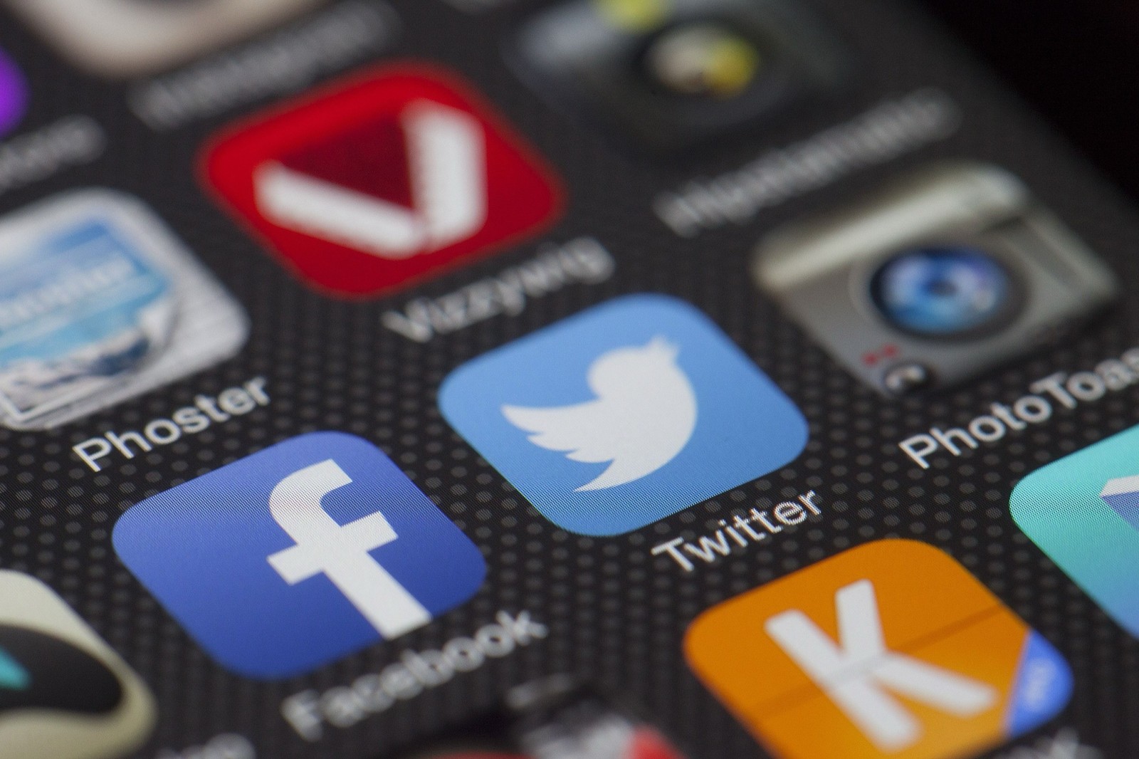 A close up of a phone screen showing social media apps, including Facebook and Twitter.