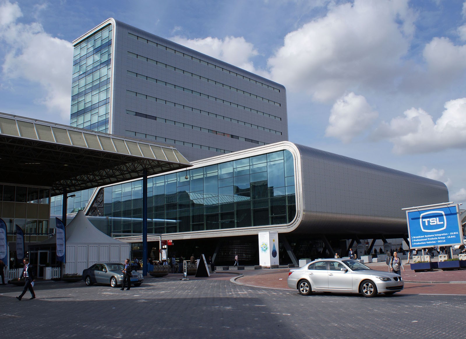 The RAI conference centre situated in the outskirts of Amsterdam; a modern looking building with a long base and tall skyscraper-esque protrusion. The frontage is entirely glass surrounded by a chunky steel exterior.