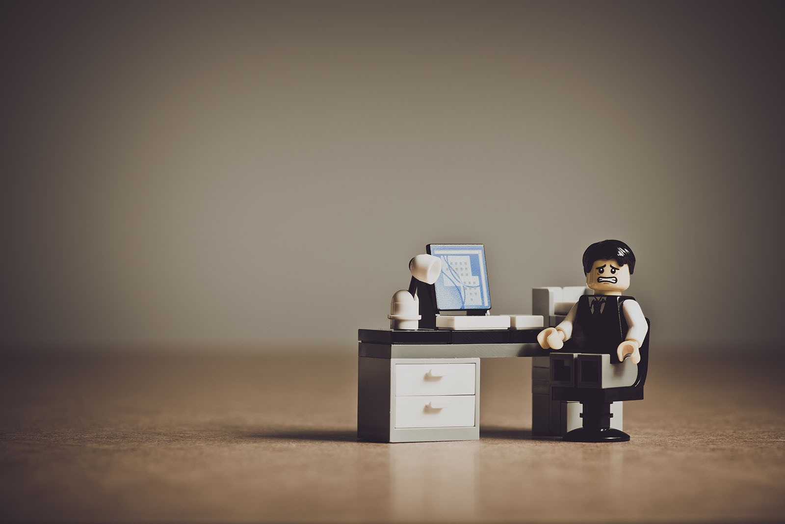 A lego man looking frustrated next to a laptop.