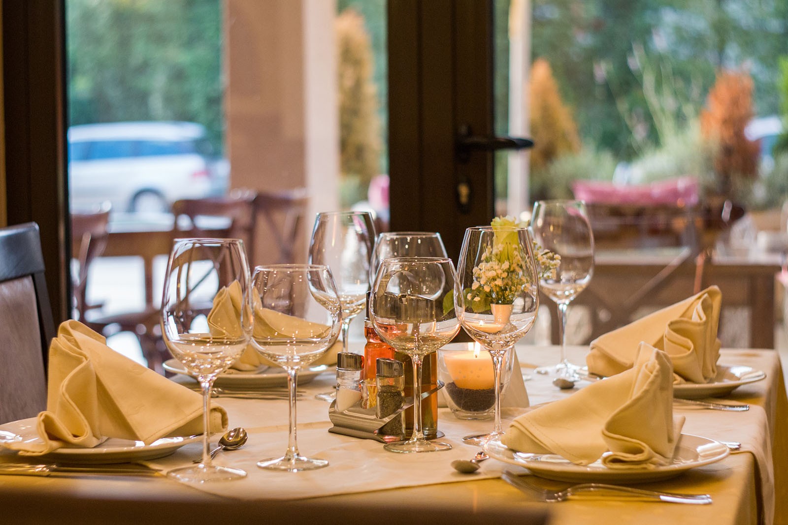 A restaurant table setting, with plates, decorative napkins and wine glasses, all made up ready for diners to arrive.