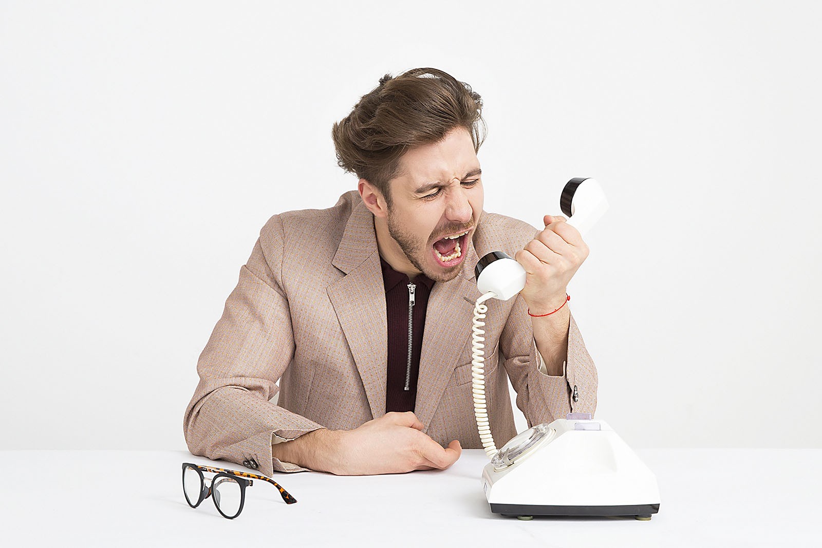Angry man shouting through the handset of a traditional phone.