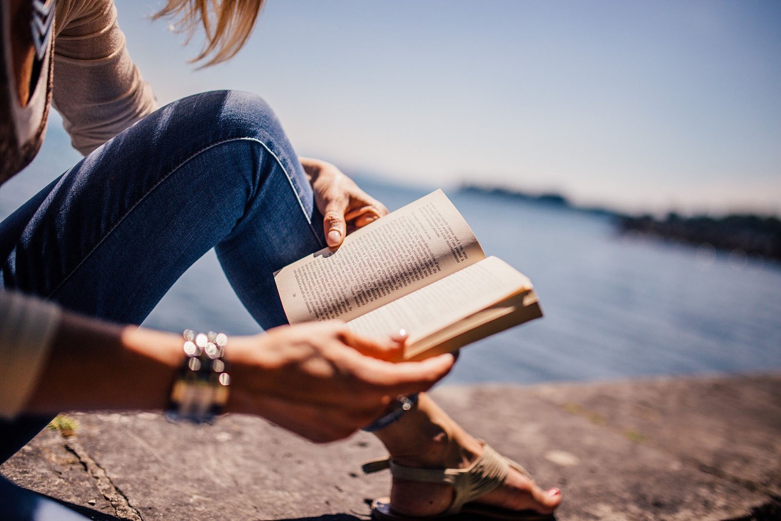 A woman reading a book on a beach.
