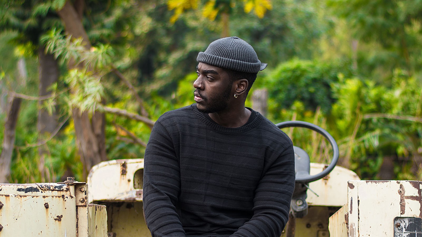 A young African farmer resting on the back of his pickup.
