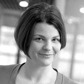 Claire Hughes with a gentle smile and a short bob with a side fringe, wearing a scoop-neck top.