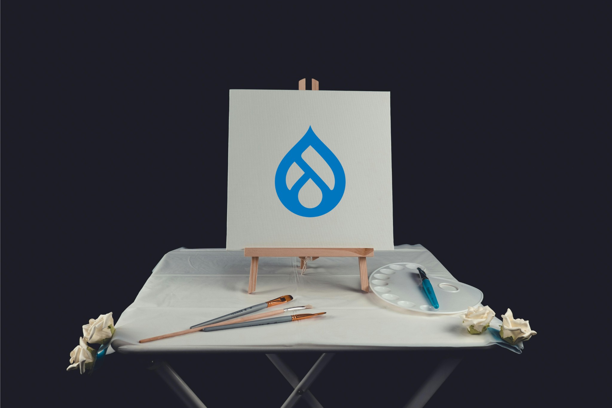 Blank canvas on table with brushes and paint palette.