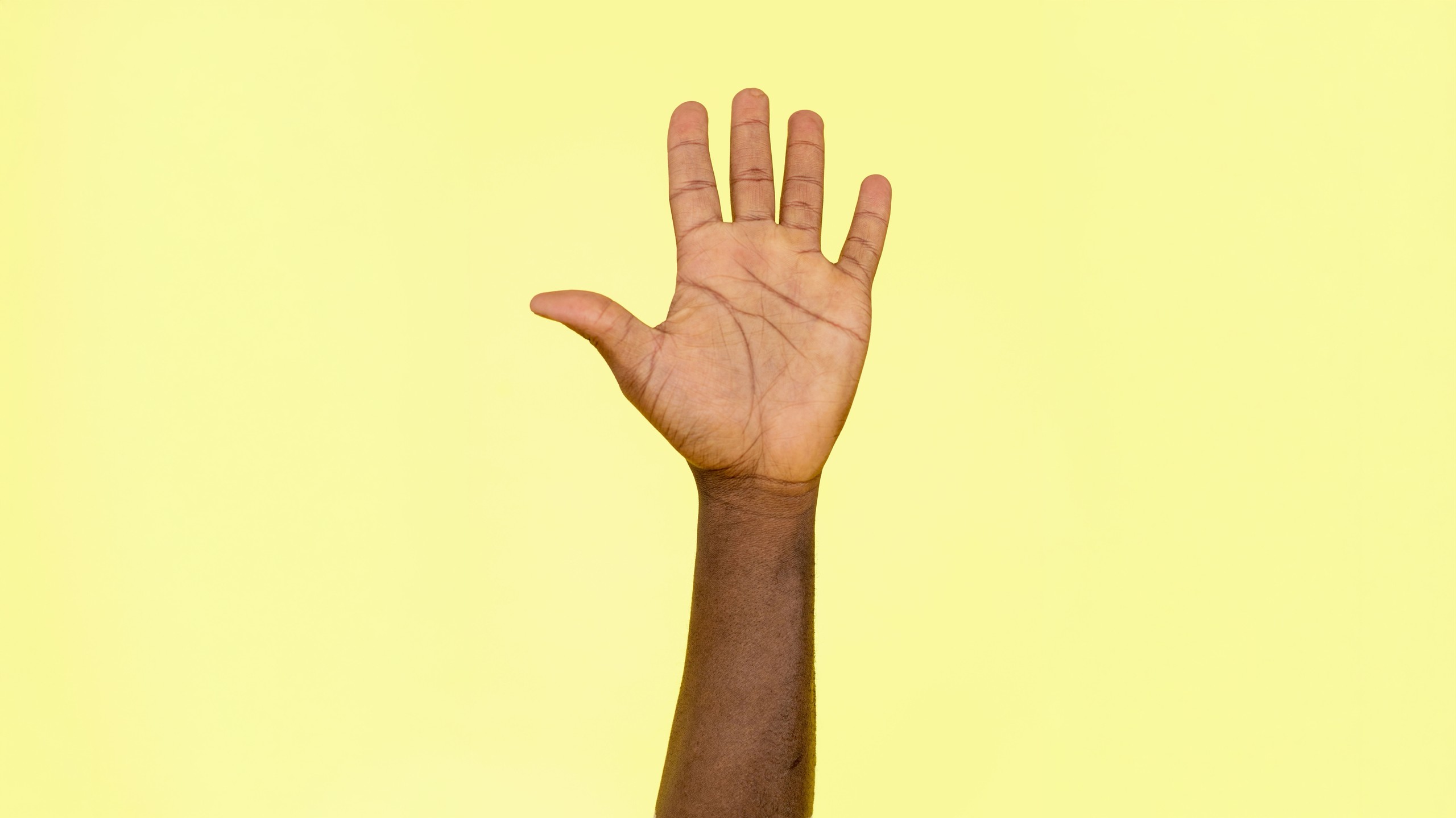 A hand with all four fingers and thumb up signifying '5 of something' on a yellow backdrop.
