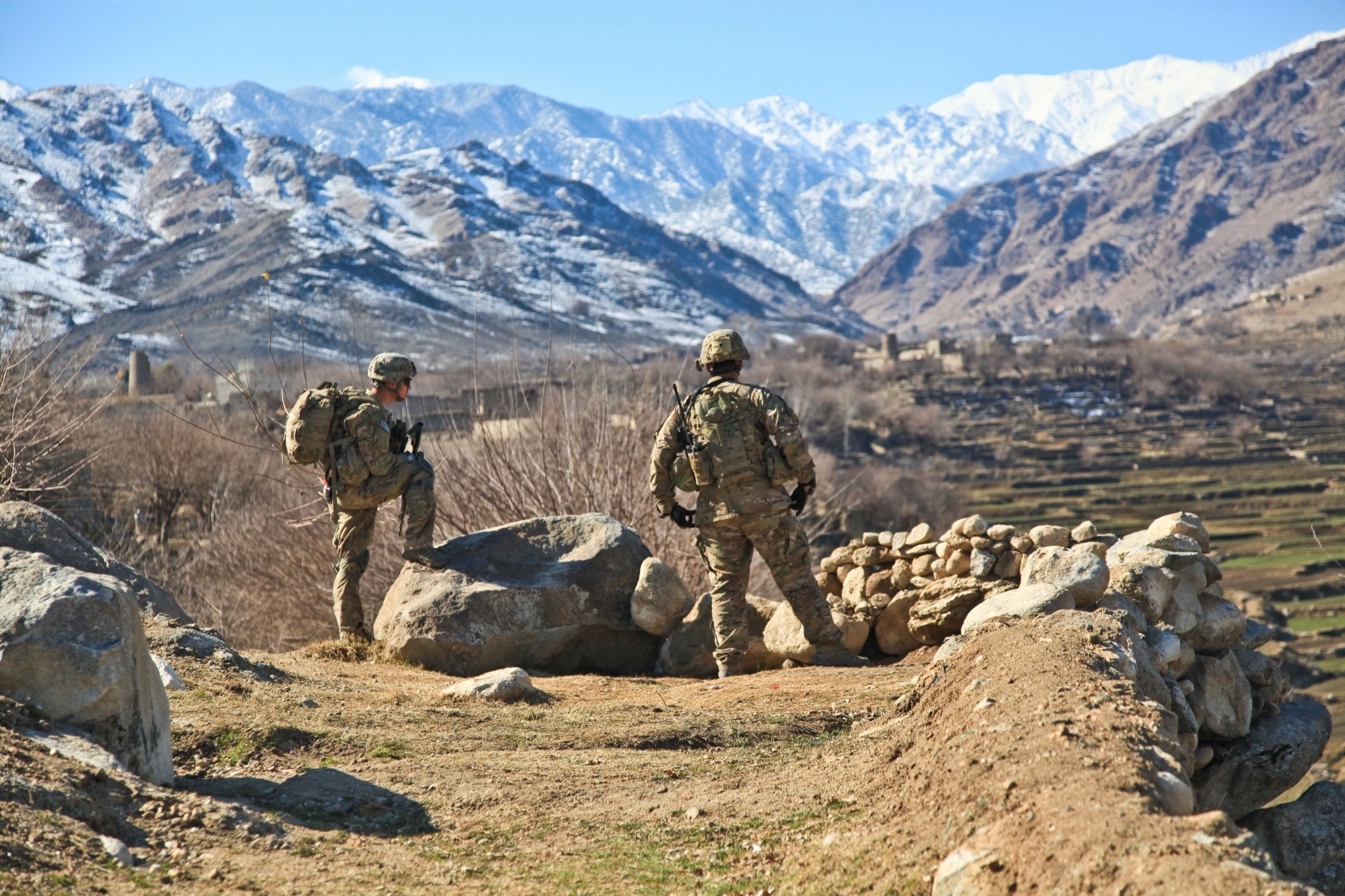 Two soldiers in Afghanistan looking out over a mountain valley.